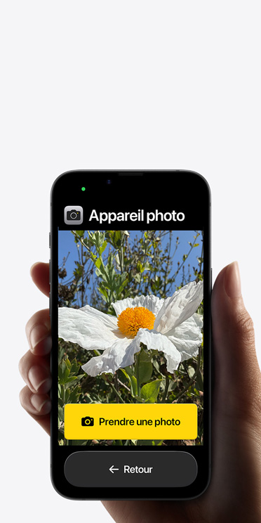 écran d’un iPhone seize-e montrant l’interface simplifiée de l’app Appareil photo. Une fleur rose est dans le cadre et le bouton Prendre une photo et celui de retour sont en dessous.