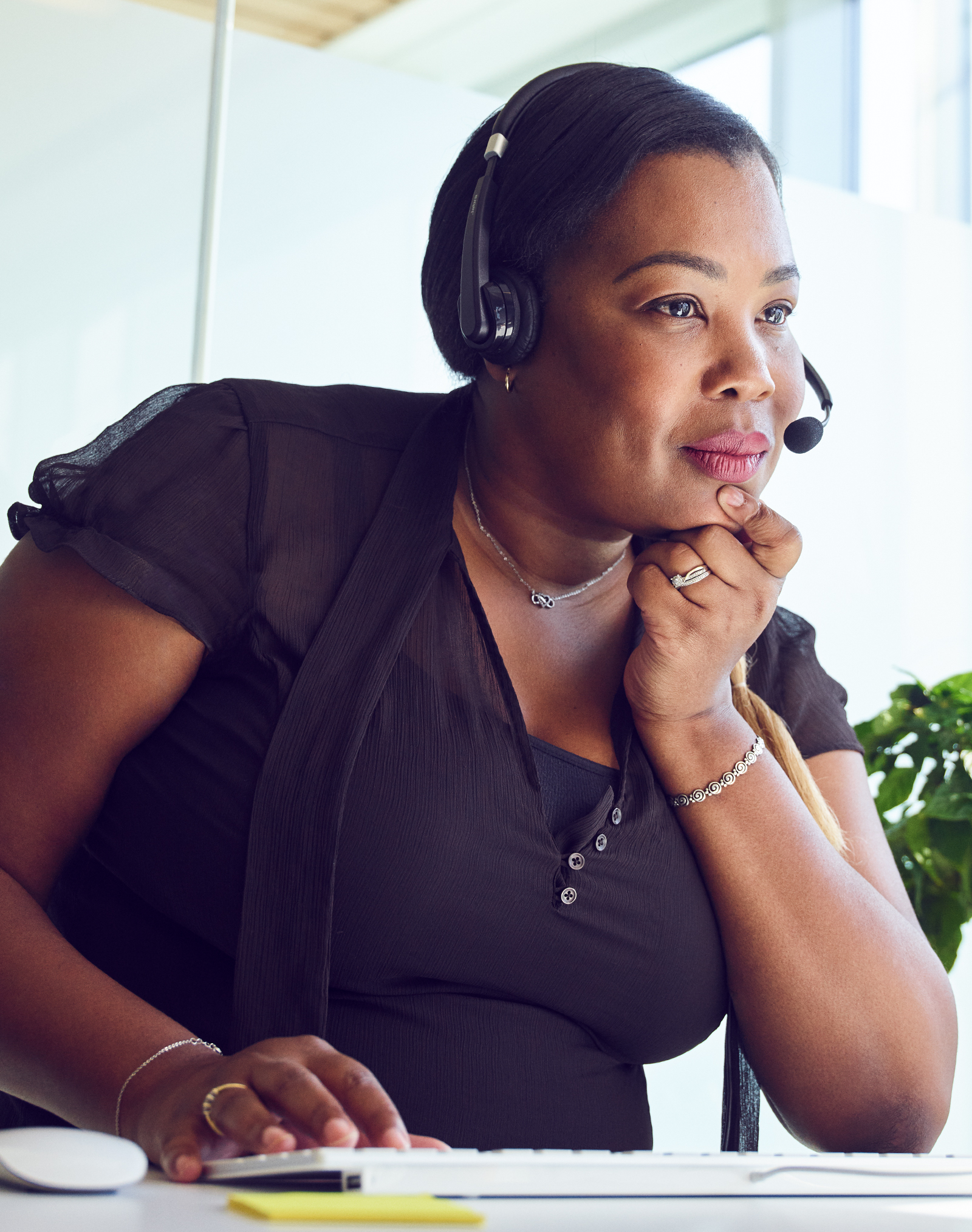 A female Apple Support Advisor wearing a headset looks at her display during a call.