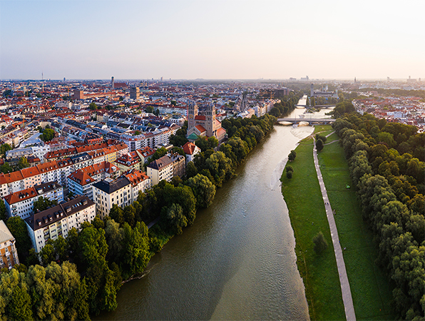 Flyfoto av München med en elv, tr?r og en gangvei langs elven.