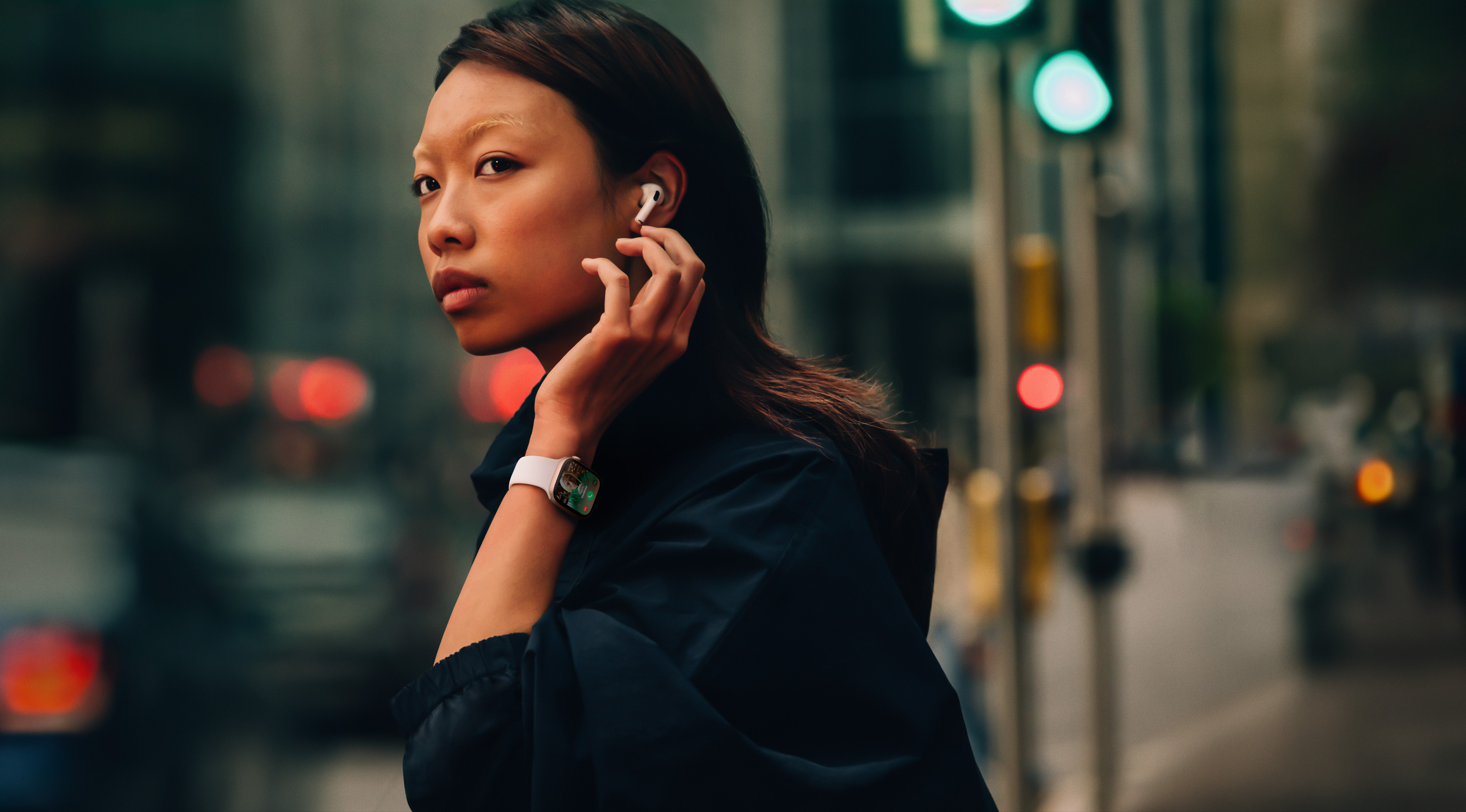 A woman on a street wearing Apple?Watch Series?10 and AirPods.