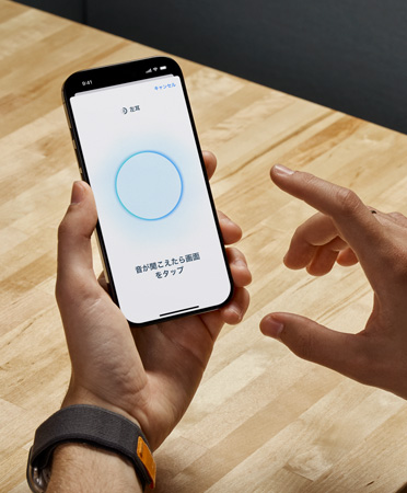 AirPods Pro 2のユーザーが、iPhoneを手に持って新しいヒアリングチェック機能を使っている