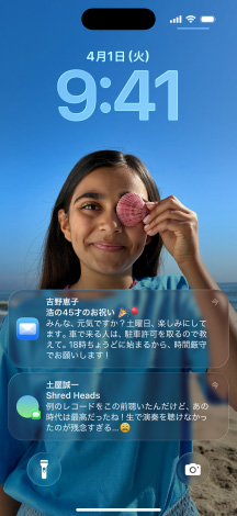 5つのiPhoneのモデル。各モデルが隣のモデルと少しずつ重なっている。左端の畫面にはメッセージアプリの背景を設(shè)定した會(huì)話、左から2番目の畫面にはカラフルなアプリのアイコンを表示したホーム畫面、中央のモデルには寫真、Liquid Glassでできた時(shí)刻を表す數(shù)字、畫面下部に2つの通知を表示したロック畫面、右から2番目のモデルにはクリアなLiquid Glassでできたアプリのアイコン、右端のモデルにはLiquid Glassのミュージックプレイヤーが映し出されている