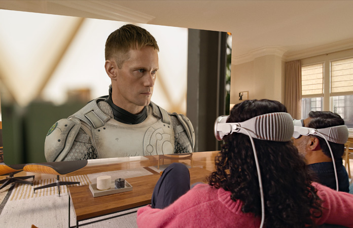 Apple Vision Proを裝著した2人がソファに並んで座り、部屋いっぱいに広がるスクリーンに映し出される「マーダーボット」を観ている