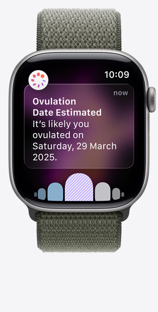 Apple?Watch Series?11，太空灰鋁金屬錶殼，展示透過健康?app 經(jīng)期追蹤收到的排卵日期推算通知、數(shù)碼錶冠，配搭森林色運動手環(huán)