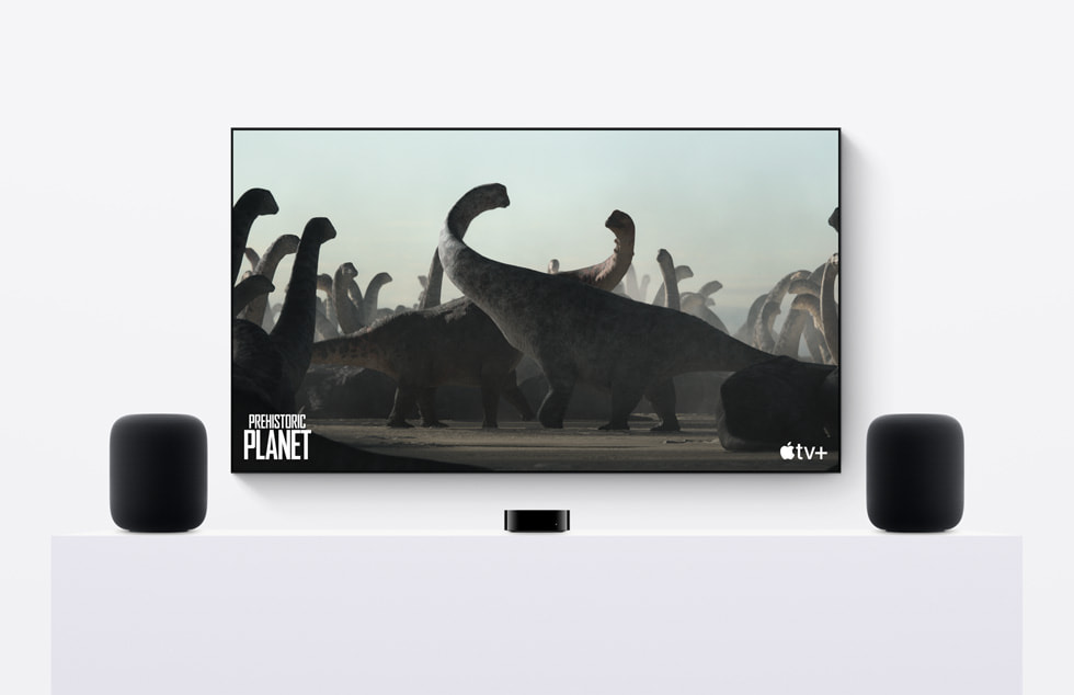 A pair of HomePod (2nd generation) speakers sit next to Apple TV where Apple TV+’s Prehistoric Planet is playing.