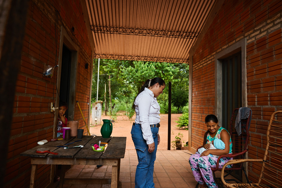 Gladys Nu?ez stands in a walkway facing a person holding a baby as a child looks on from a doorway.