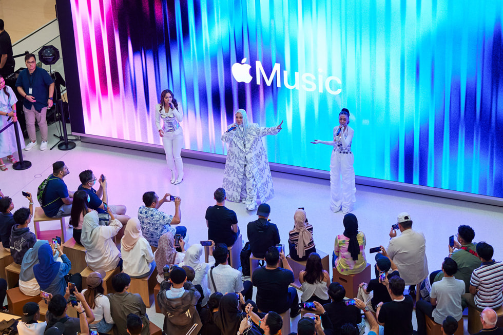 Hình ?nh toàn c?nh màn trình di?n c?a De Fam dành cho khán gi?, v?i logo Apple Music trên màn hình phía sau ban nh?c. 