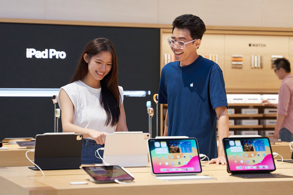 Khách hàng và nhan viên ?ang ??ng t?i bàn tr?ng bày iPad c?a c?a hàng. 