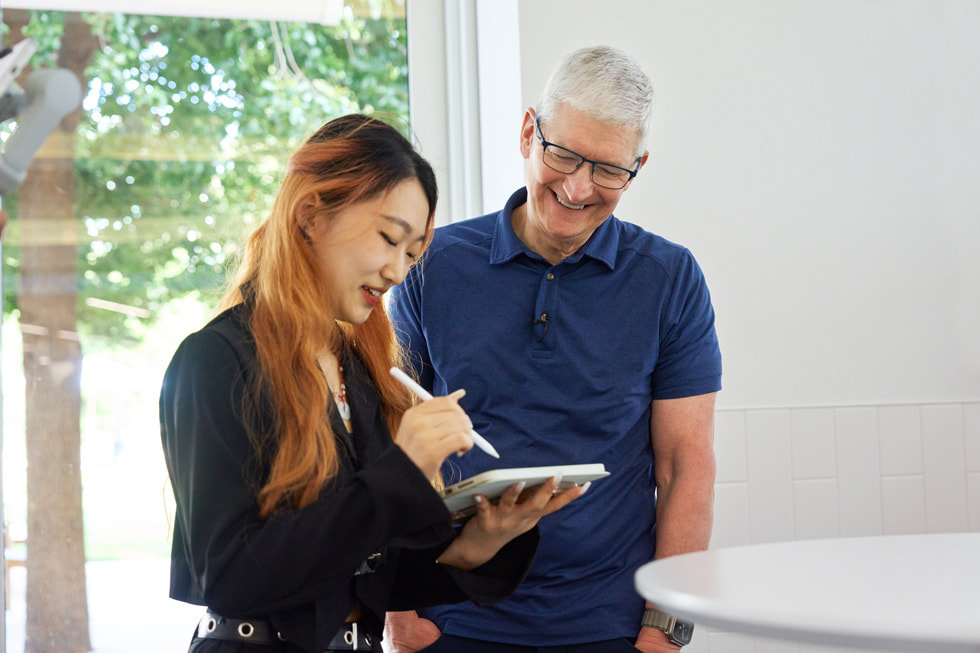 Elinde iPad ile Apple Pencil tutan bir geli?tiricilik ??rencisinin Tim Cook ile foto?raf?.