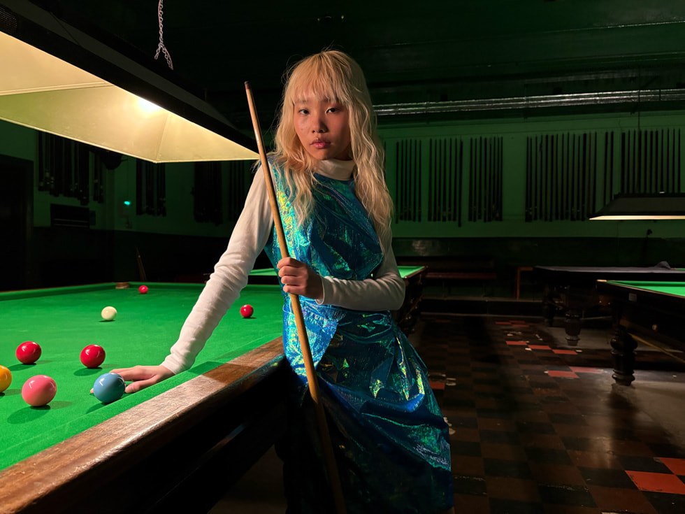 Lo? ???kl? bir odada bilardo masas?n?n kar??s?nda poz veren bir ki?i.