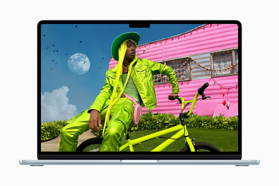MacBook Air shows a stylized photo of a person in a neon-green outfit sitting on a neon-green bicycle in front of a neon-pink motorhome. 