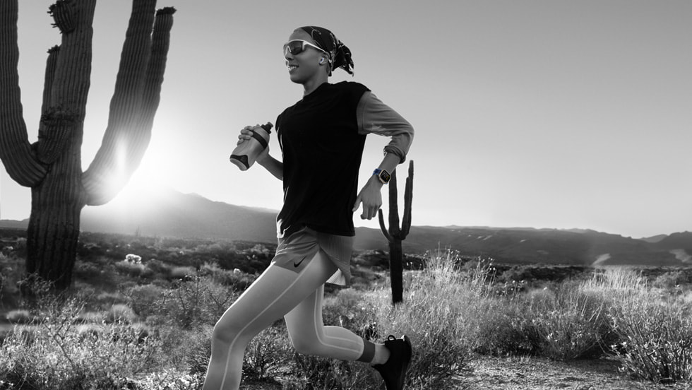 A black-and-white photo of a runner passing through a desert landscape wearing Apple Watch Ultra 3.
