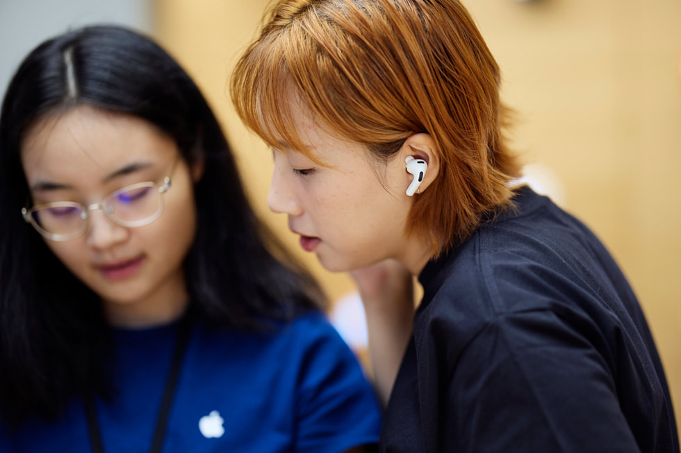 上海 Apple 南京東路零售店內，一位 Apple 團隊成員協(xié)助顧客試用 AirPods Pro 3。