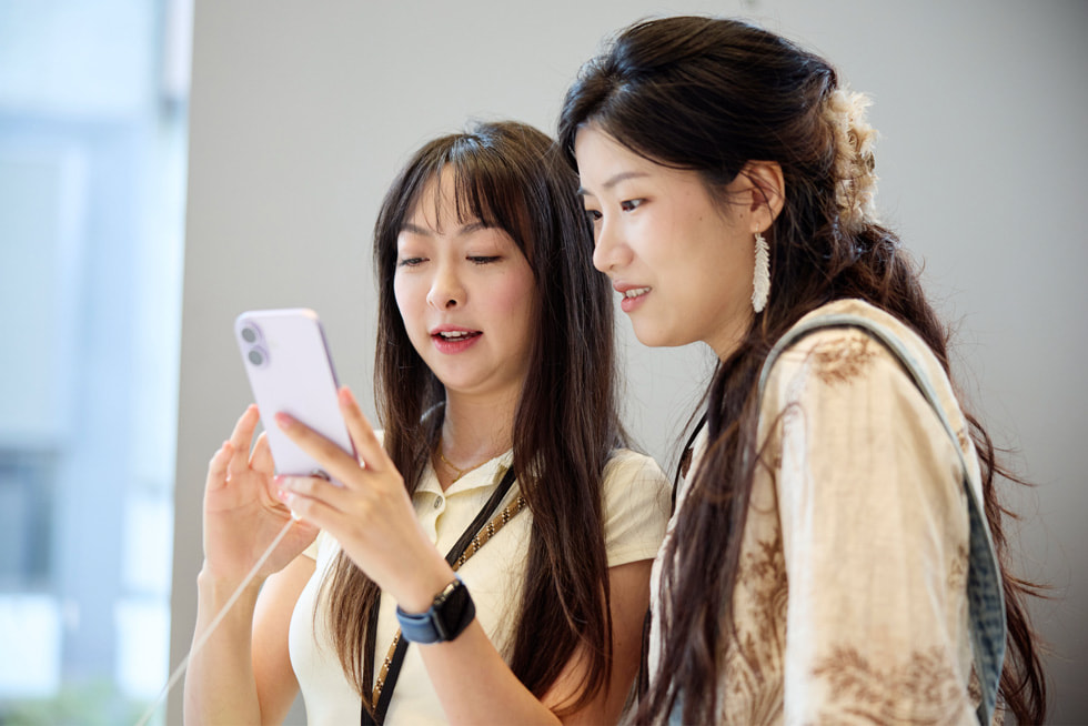 上海 Apple 南京東路零售店內，兩位顧客試用全新 iPhone 17。