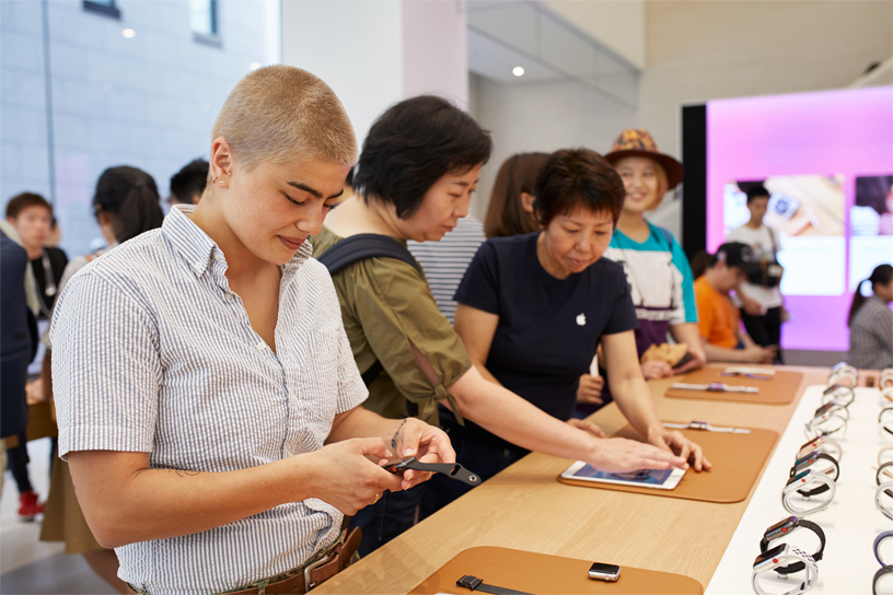 Apple Kyoto’daki bir masada Apple Watch’lara bakan insanlar.