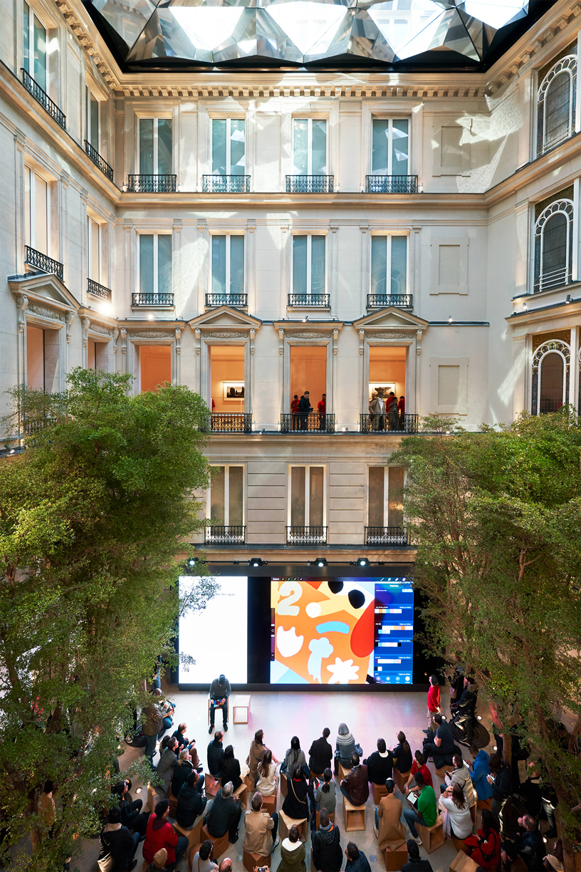 Kalabal?k bir mü?teri toplulu?u Apple Champs-élysées’deki Forum alan?nda oturuyor.