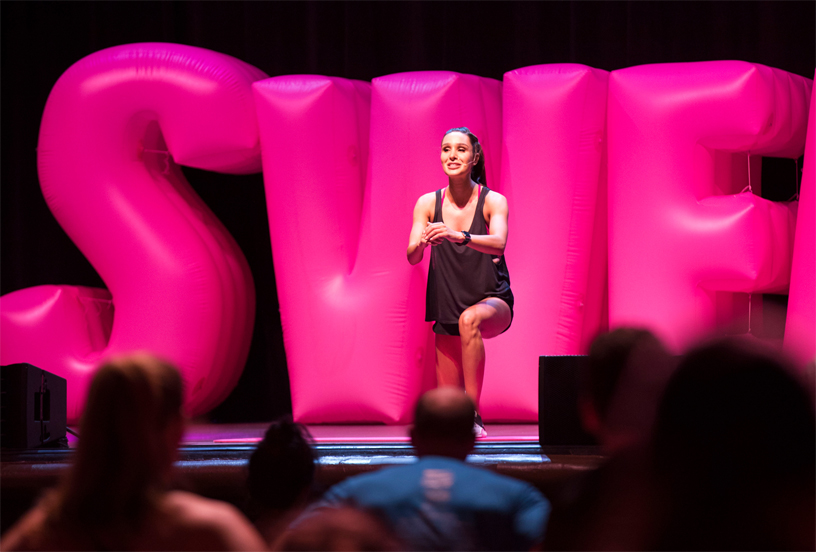 Kayla Itsines sahnede ?i?irilmi? balon harfler ?nünde fitnes rutinini yap?yor. 