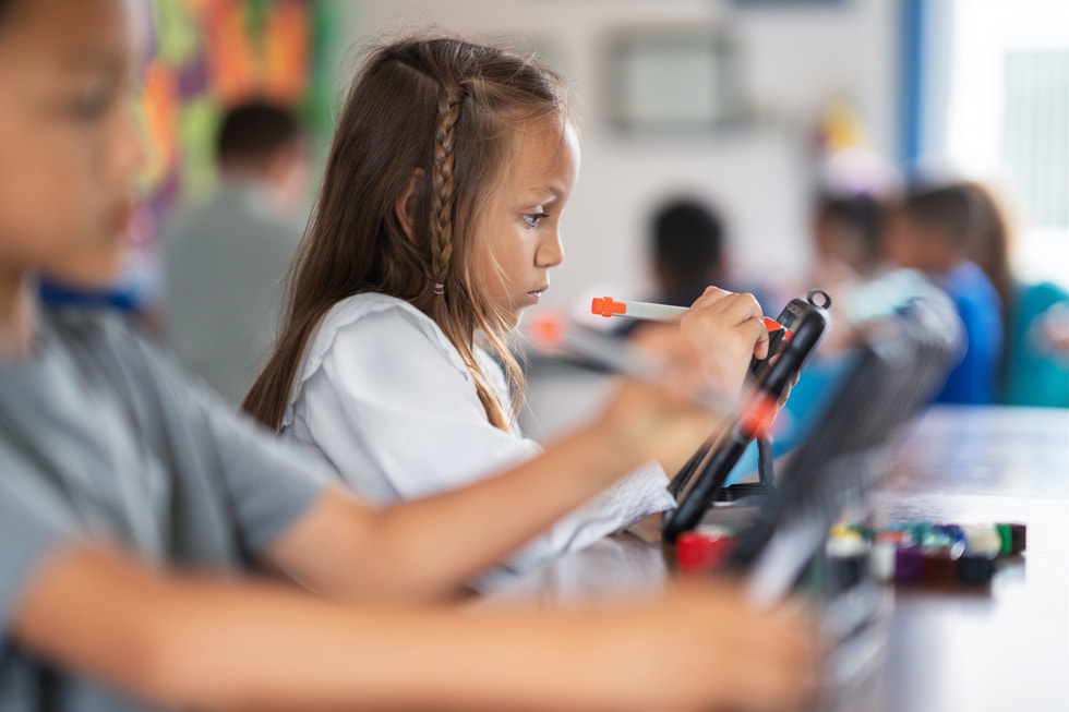 Gen? bir ??renci s?n?fta iPad’in üzerinde bir stylus kalem tutuyor.