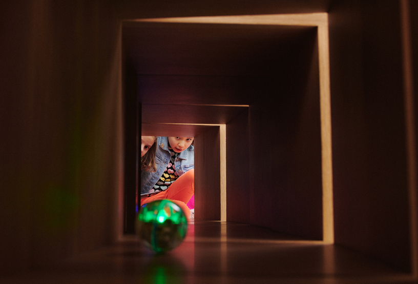 Two girls peering through a tunnel.