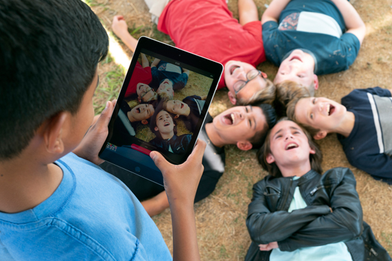 Bir ??renci iPad kullanarak s?n?f arkada?lar?n?n foto?raf?n? ?ekiyor.