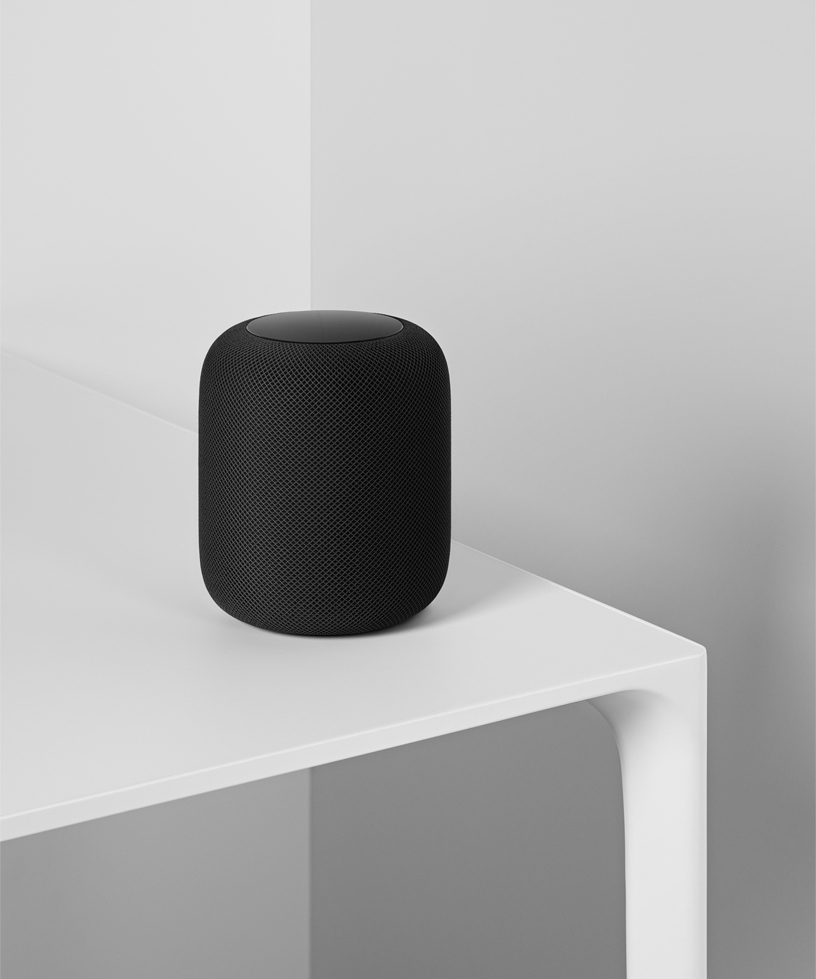 Beyaz masan?n üzerinde duran siyah bir HomePod’un foto?raf?. 