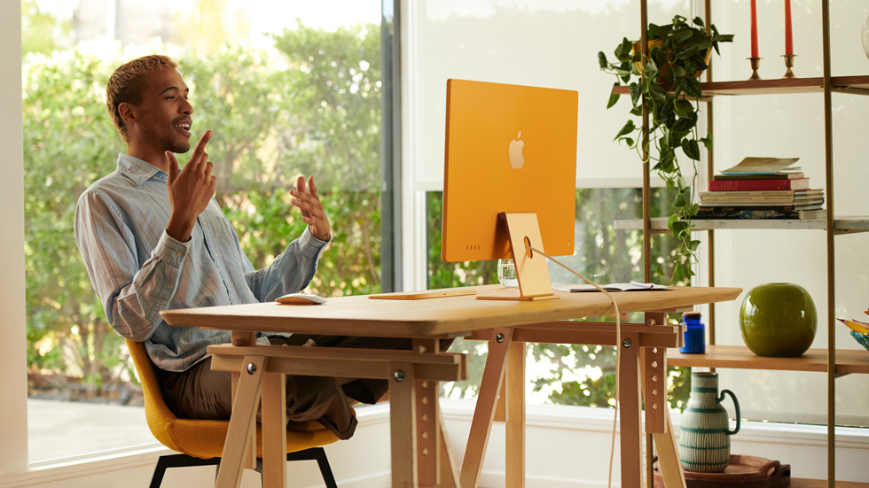 Bir adam evindeki ofise kurdu?u yeni turuncu iMac’ini kullan?yor.