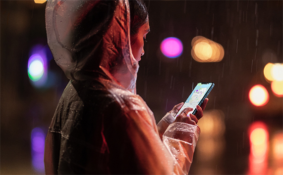Ya?murun alt?nda elinde iPhone XR tutan kad?n.