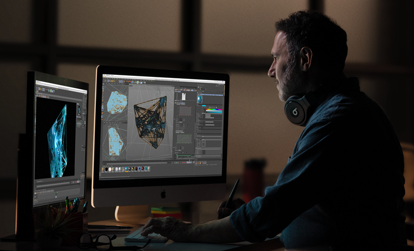 Bir iMac ve ek bir monit?rde 3D grafikleri g?zden ge?iren bir profesyonel.