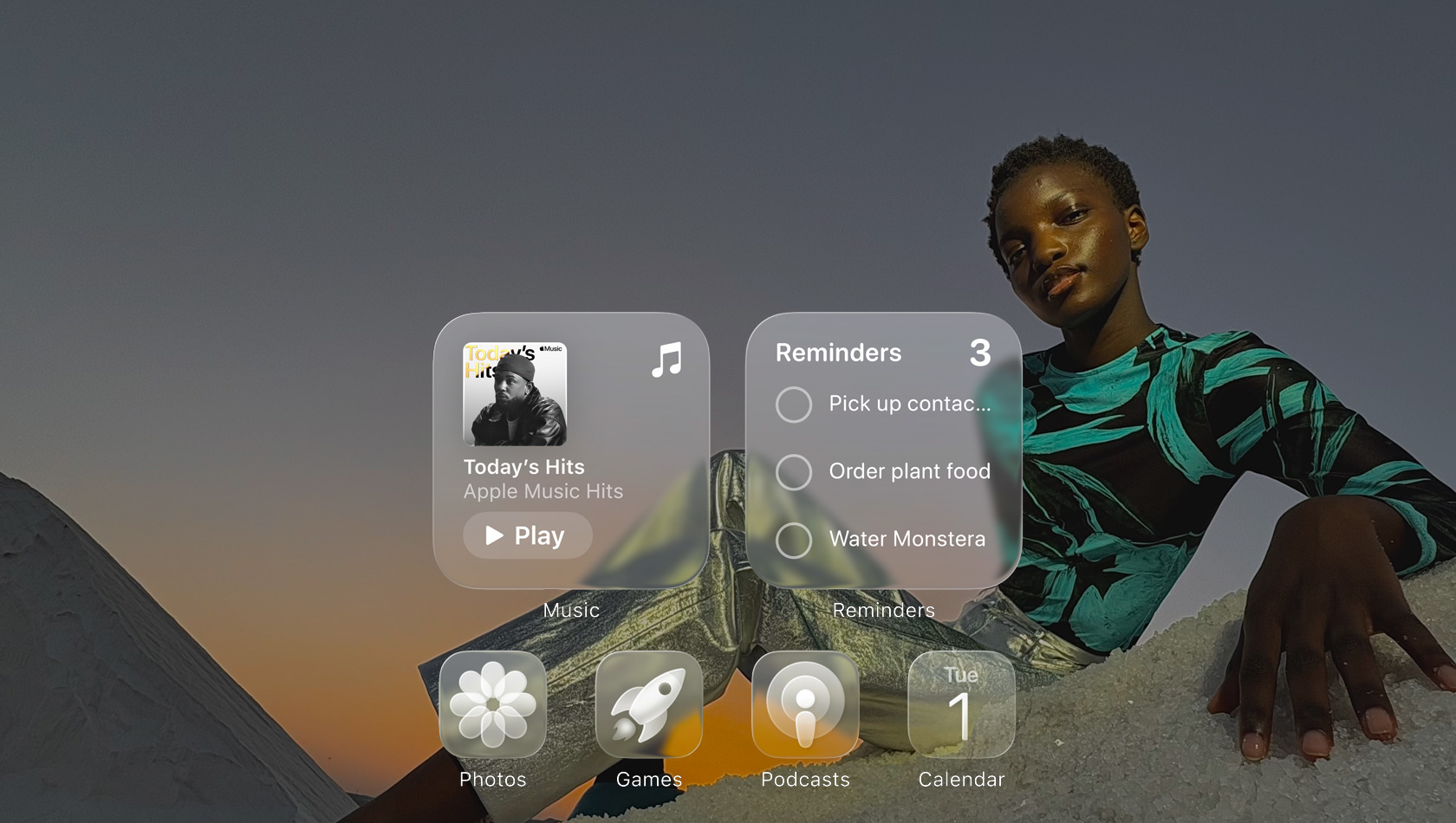 Displej v Liquid Glass designu s pr?svitnymi ikonami aplikací jako Apple Music, P?ipomínky, Fotky, Hry, Podcasty a FaceTime, p?es které prosvítá tapeta