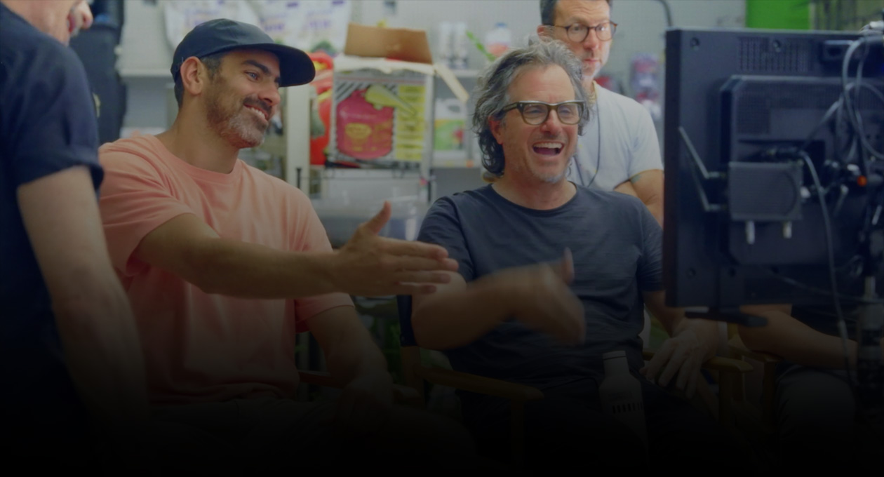 Image de deux cinéastes masculins regardant un écran de projection et faisant des signes.