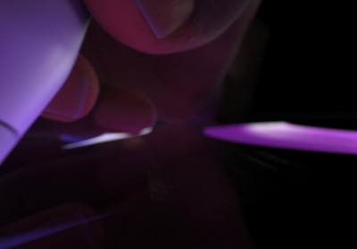 Una mano sostiene un Apple Pencil Pro en posición para escribir. La punta presiona sobre una pantalla en la que se muestran trazos gruesos en morado brillante.