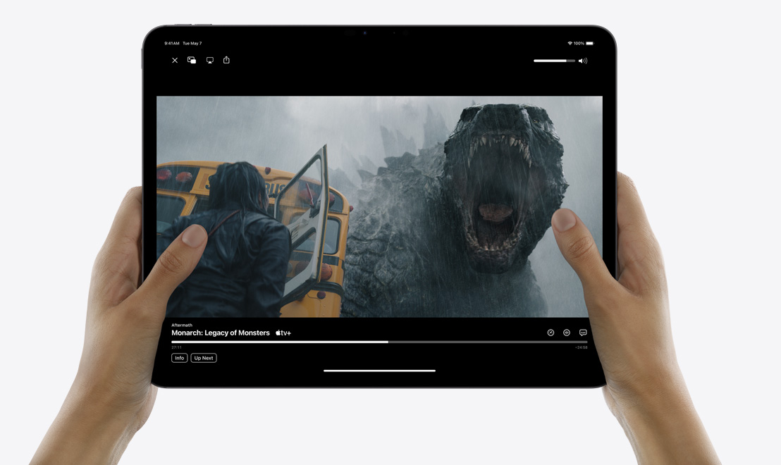 Deux mains tenant un iPad Pro montrant l’app TV diffusant la série ? Monarch: Legacy of Monsters ?.