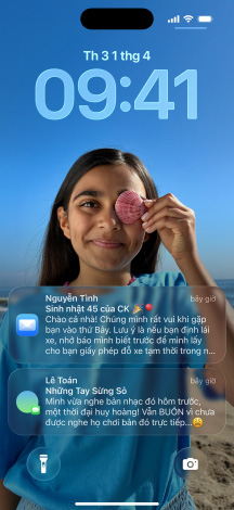 N?m phiên b?n iPhone, m?i phiên b?n h?i x?p ch?ng lên phiên b?n bên c?nh, màn hình ngoài cùng bên trái hi?n th? cu?c trò chuy?n v?i n?n trong Tin Nh?n, màn hình th? hai bên trái hi?n th? Màn Hình Chính v?i các bi?u t??ng ?ng d?ng ??y màu s?c, phiên b?n ? gi?a hi?n th? Màn Hình Khóa(chǎn) v?i ?nh, các ch? s? cho bi?t th?i gian theo phong cách Liquid Glass, hai th?ng báo xu?t hi?n ? cu?i màn hình, phiên b?n th? hai bên ph?i hi?n th? các bi?u t??ng ?ng d?ng theo phong cách Liquid Glass trong su?t, phiên b?n ? ngoài cùng bên ph?i hi?n th? trình phát nh?c theo phong cách Liquid Glass